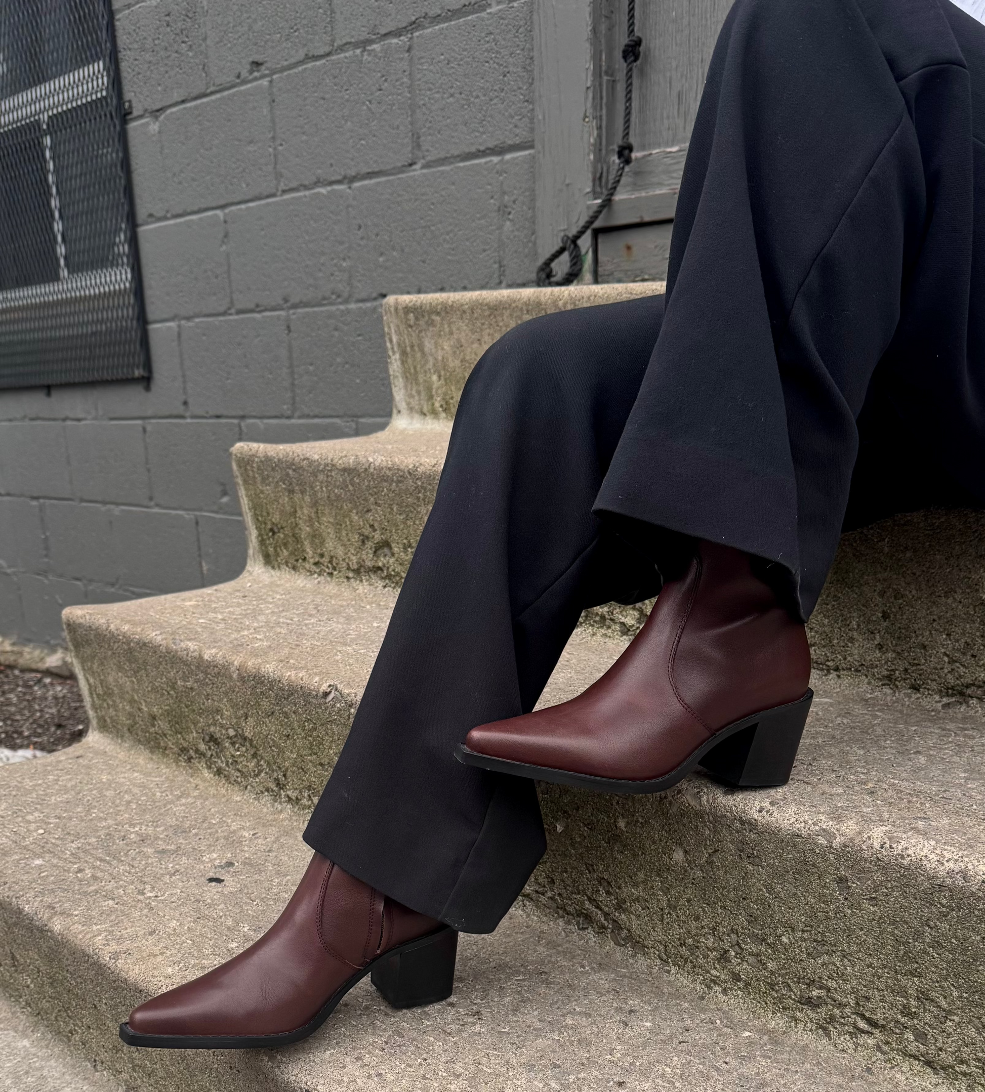 Person wearing dark pants and brown shoes sitting on concrete steps.