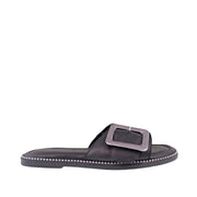 Black leather slip-on sandal with oversized buckle detail on a white background.