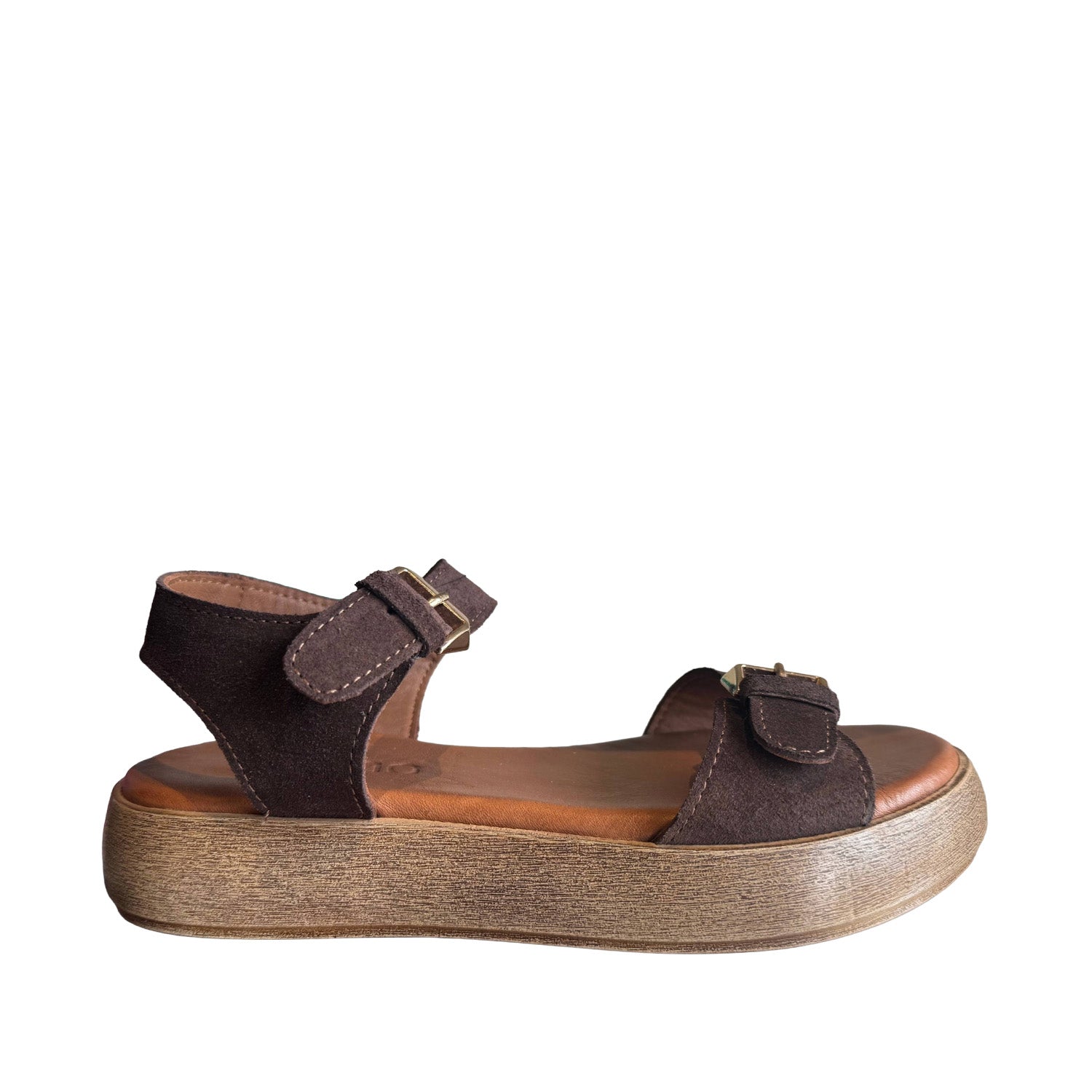 Brown suede sandal with adjustable buckle straps at the ankle and toe, on a white background.