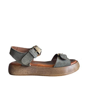 Green suede sandal with adjustable buckle straps at the ankle and toe, on a white background.