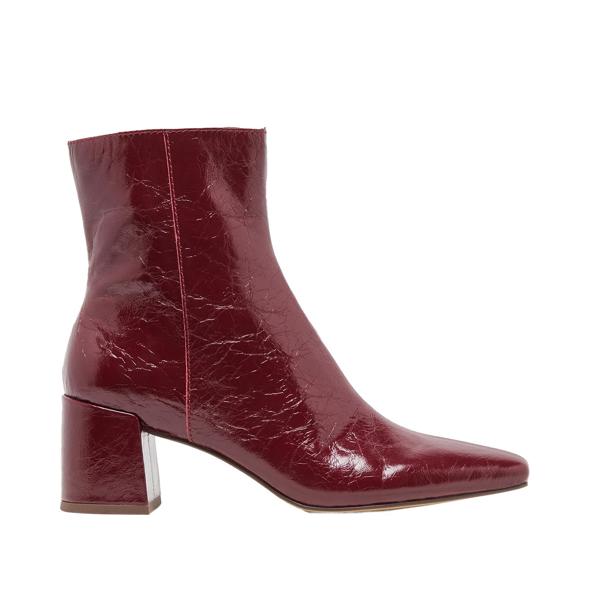 red heeled patent leather ankle boot on a white background
